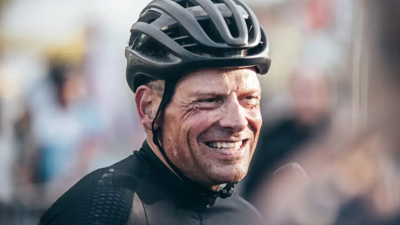 Jan Ullrich, lachend mit Helm und Radsportkleidung, spricht ins Mikrofon. Was macht Jan Ullrich heute? Er teilt seine Gedanken.