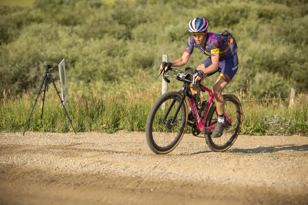 Tiffany Cromwell fährt mit ihrem pinken Gravelbike auf einer staubigen Strecke.