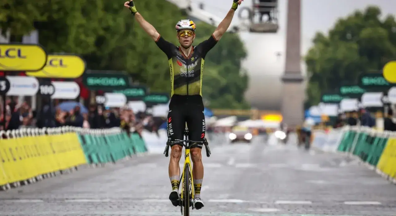 Wout van Aert jubelt mit erhobenen Armen über die Ziellinie.