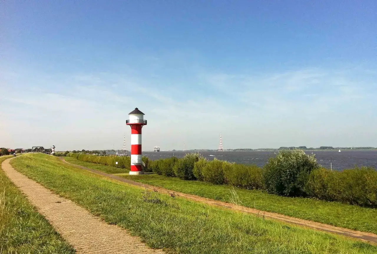 Rennrad strecken Hamburg: Leuchtturm mit roten und weißen Streifen am Elbufer, ideal für eine Radtour.