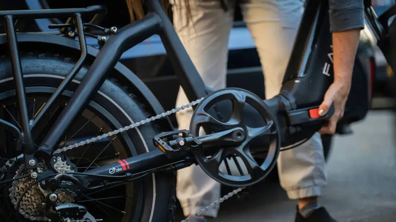 Nahaufnahme eines E-Bikes mit Kette und Kurbel. Eine Hand h&auml;lt den Akku, um den Bosch CX Gen 4 leiser machen zu k&ouml;nnen.