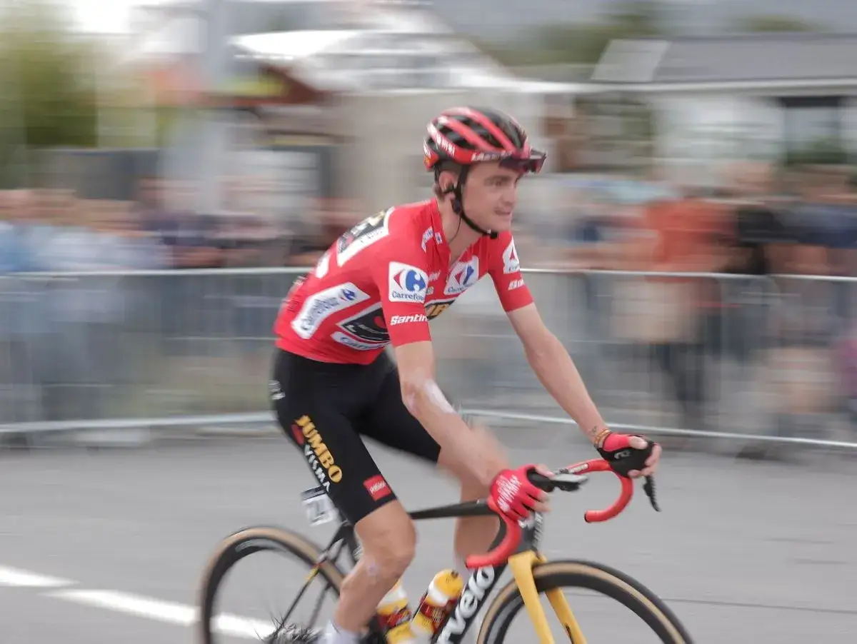 Sepp Kuss im roten Trikot von Jumbo-Visma fährt mit voller Geschwindigkeit auf seinem Rennrad.