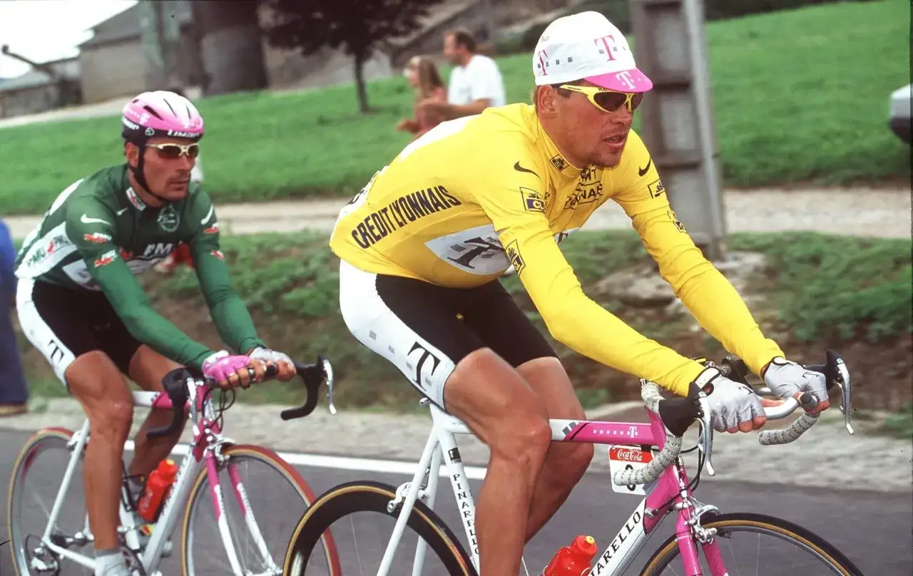 Gelbes Trikot: Ein Radfahrer, der wie ein deutscher Tour de France Sieger aussieht, fährt mit einem anderen Radfahrer im grünen Trikot.