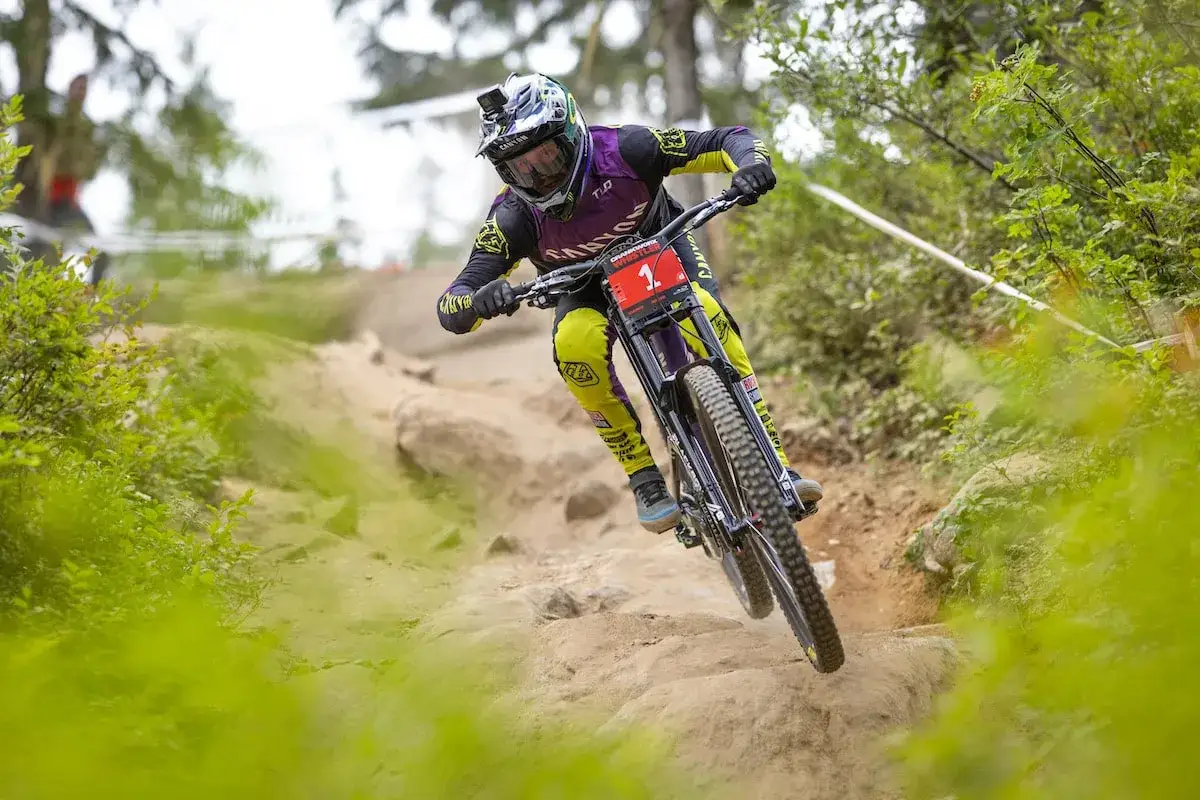 Troy Brosnan meistert eine steile Abfahrt auf seinem Downhill-Mountainbike, die Reifen greifen den felsigen Untergrund.