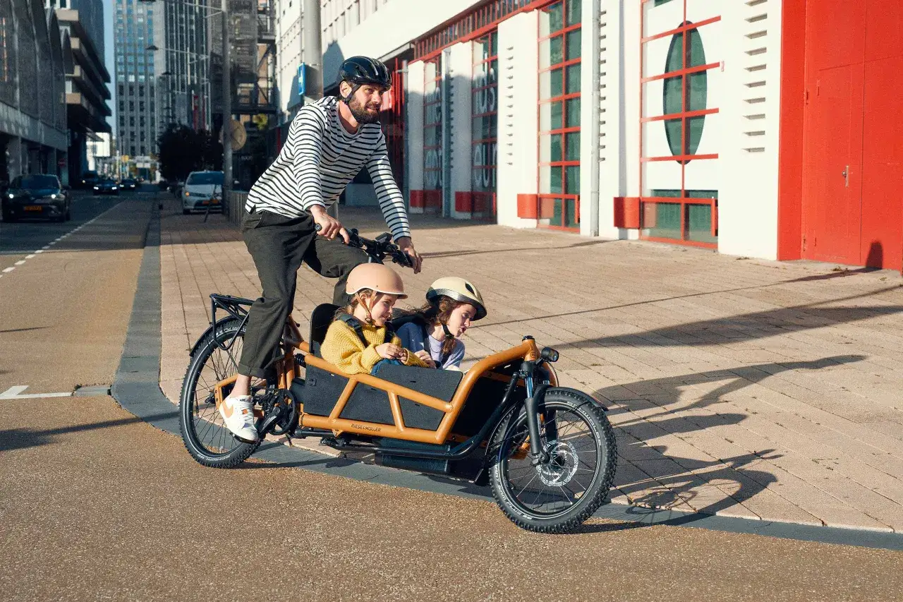 Mann mit Kindern im Lastenrad testet die Fahrt durch die Stadt.