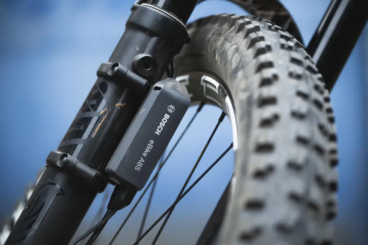Nahaufnahme eines E-Bike-ABS-Sensors von Bosch, montiert an einer Federgabel neben dem Reifen.