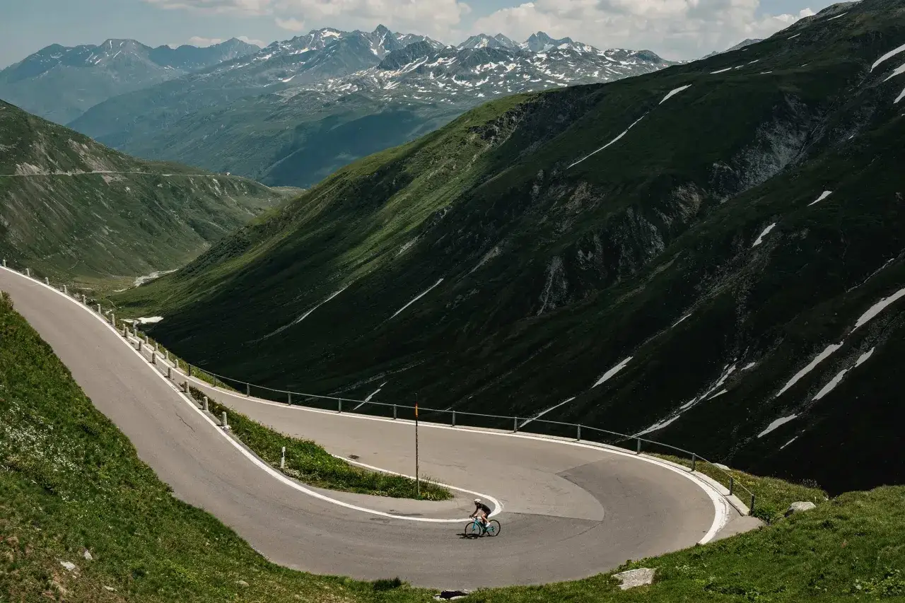 Ein Rennradfahrer meistert eine Serpentinenstraße im Hochgebirge. Ein epischer Alpencross mit Rennrad.