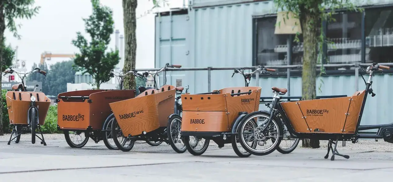 Mehrere Lastenr&auml;der mit Holzkisten stehen nebeneinander. Das Gewicht eines solchen Lastenrads ist beachtlich, aber f&uuml;r den Transport von Kindern oder Eink&auml;ufen ideal.
