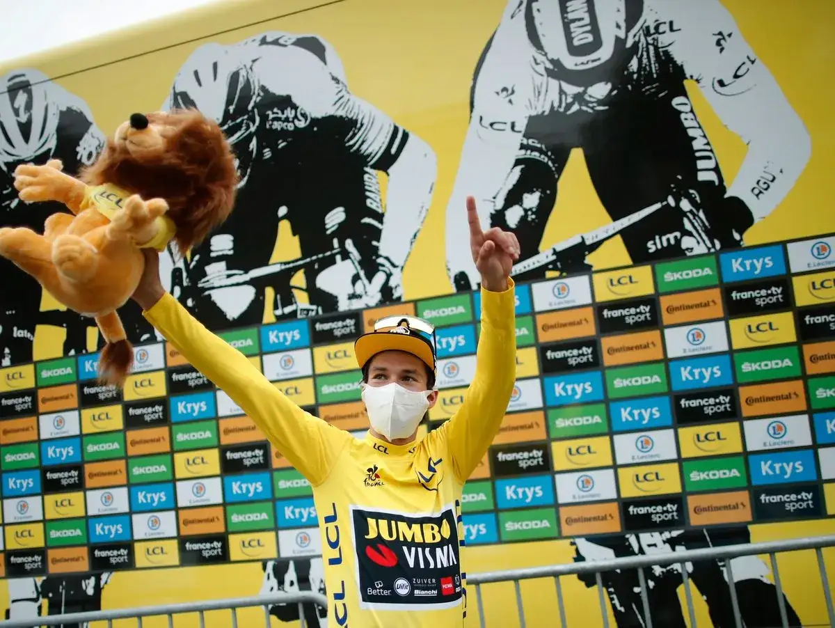 Roglic feiert mit Löwen-Stofftier und gelbem Trikot bei der Tour de France.