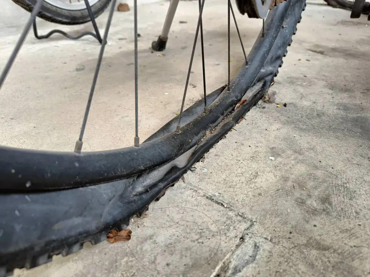 Plattfu&szlig; am Fahrradreifen, ein Nachteil von nicht pannensicheren Reifen. Der Reifen ist stark besch&auml;digt und platt.