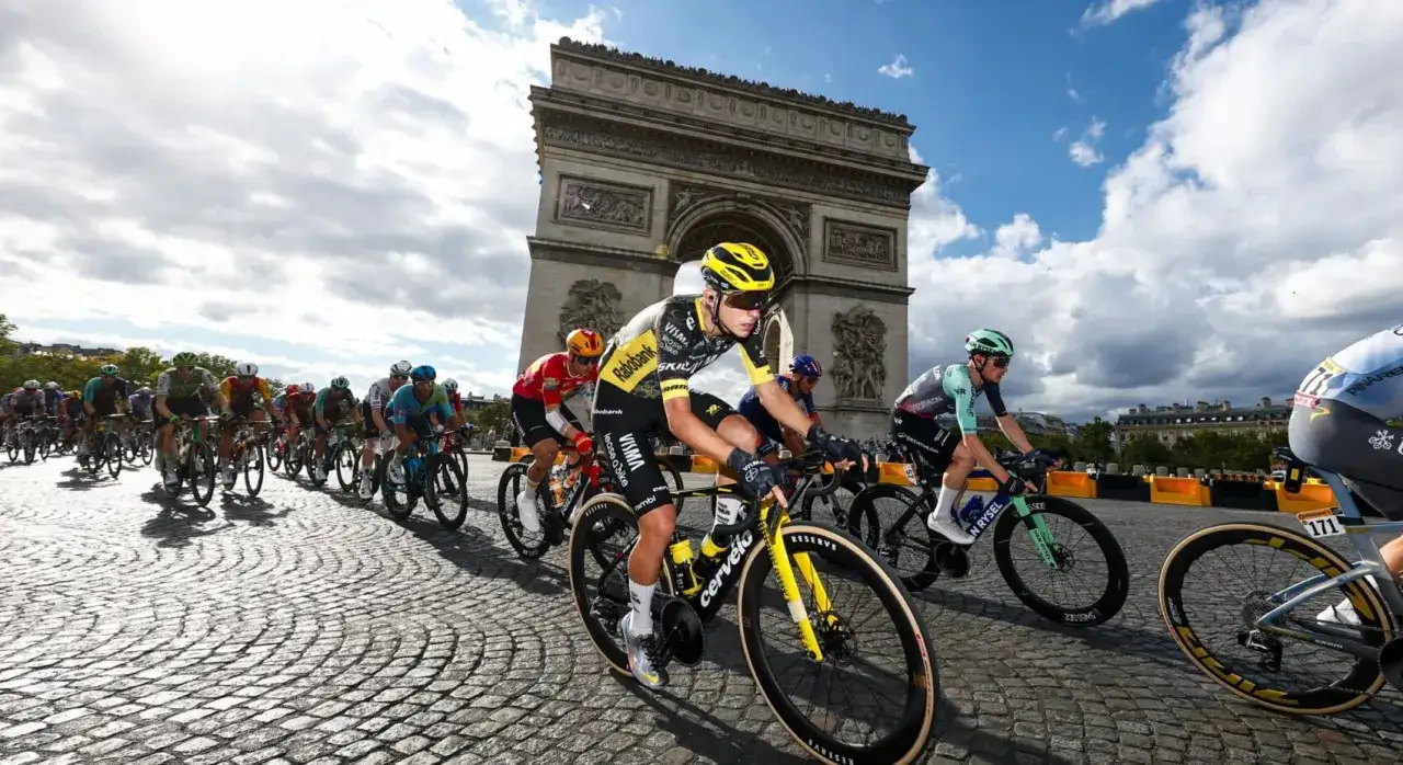 Radfahrer des Teams Jumbo-Visma fahren auf Kopfsteinpflaster vor dem Triumphbogen in Paris.
