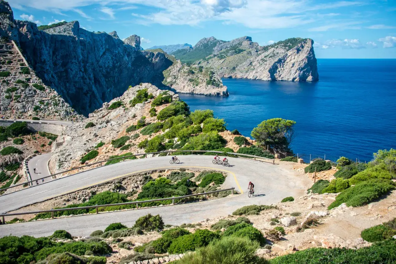 Radfahrer auf der Serpentinenstraße nach Sa Calobra, umgeben von steilen Felsen und dem tiefblauen Meer.