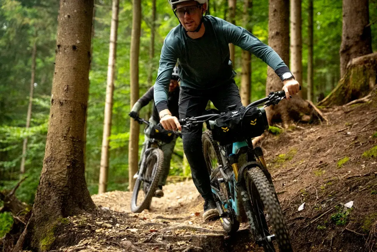 Zwei Radfahrer auf einem Waldweg, bereit für ein Bikepacking-Abenteuer.