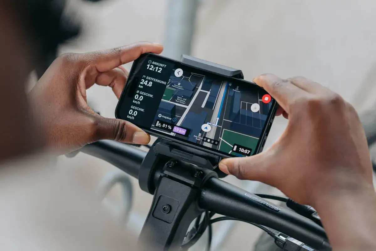 Hände halten Smartphone mit Bosch Flow App Navigation offline. Anzeige zeigt Karte, Entfernung und Geschwindigkeit.