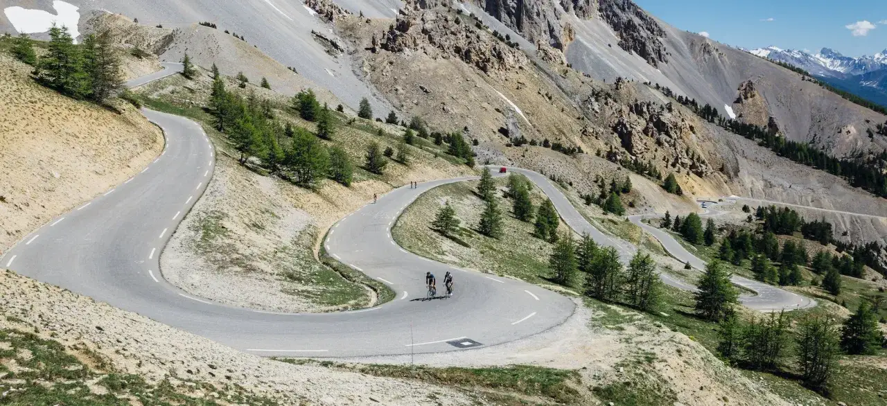 Radfahrer kämpfen sich auf Serpentinenstraßen durch die Alpen, ein Vorgeschmack auf die Tour de France 2026.