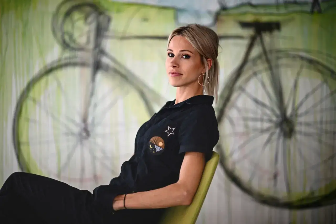Marion Rousse sitzt vor einer Wandmalerei eines Fahrrads.