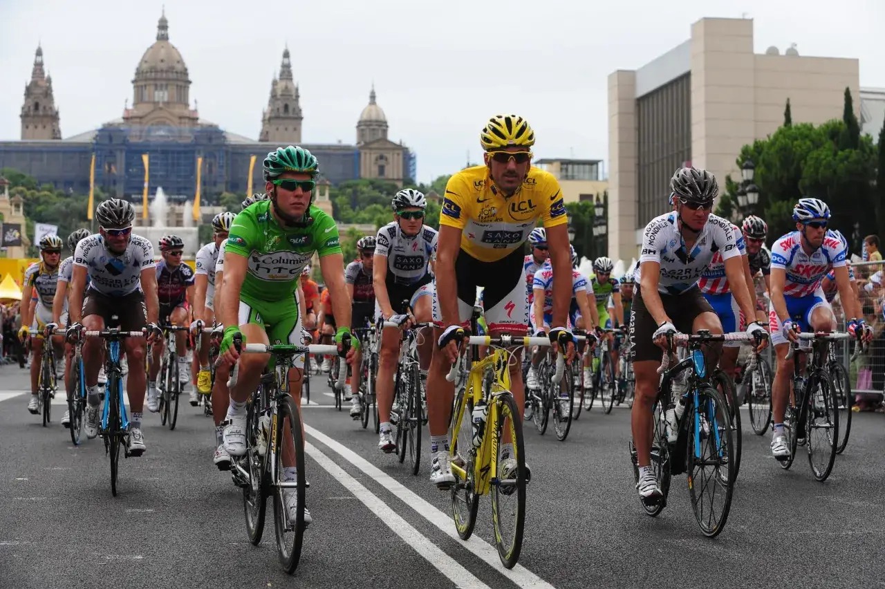Radfahrer im Peloton, bereit für den Tour de France start. Im Hintergrund das imposante Gebäude des Palau Nacional in Barcelona.