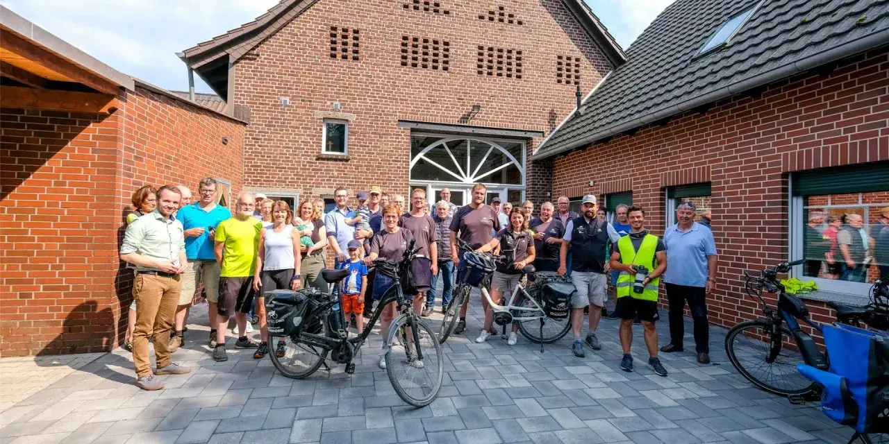 Eine fröhliche radfahrer community steht vor einem Backsteinhaus, bereit für eine Tour.