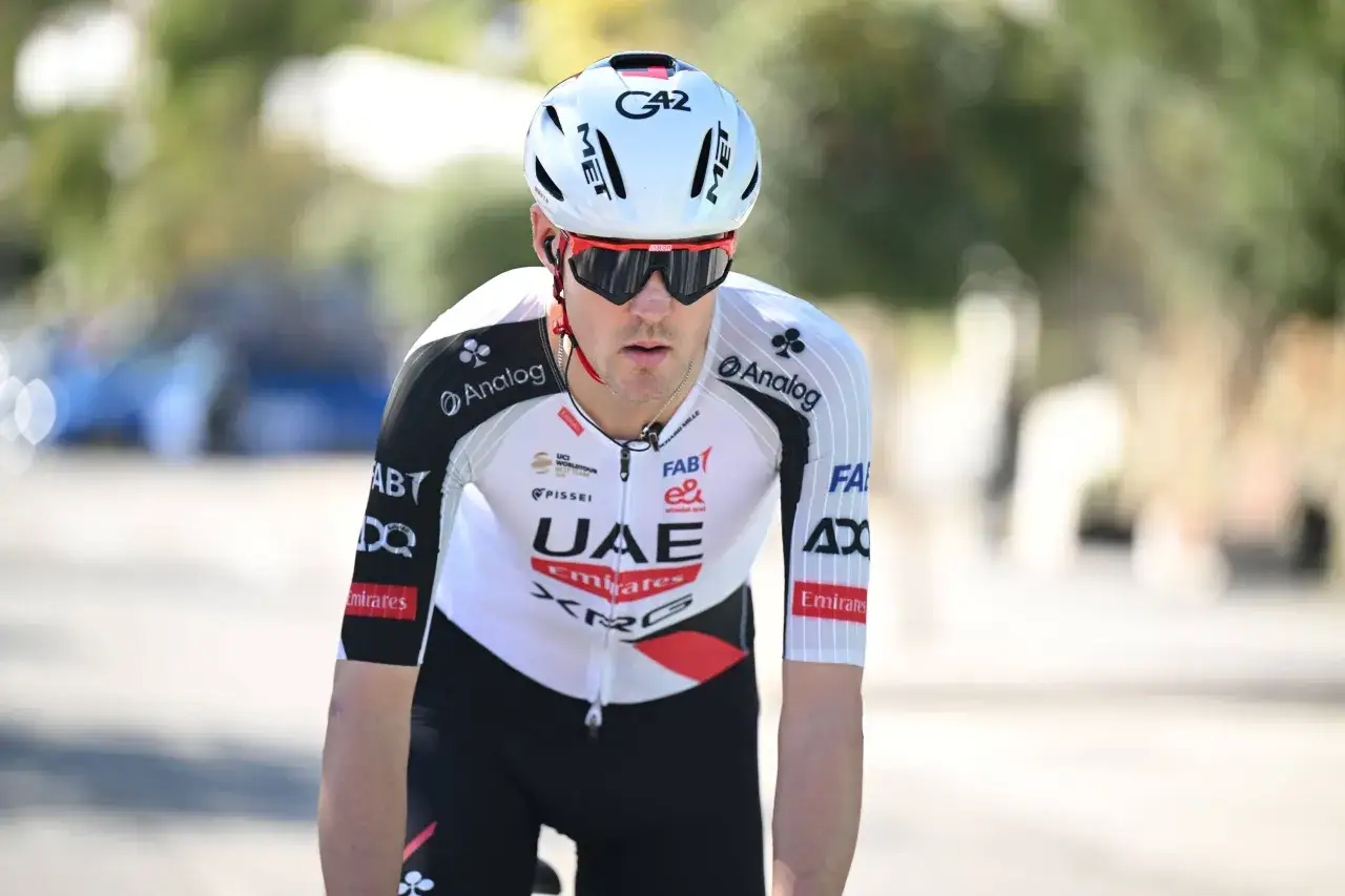 Pavel Sivakov im UAE Emirates Trikot, konzentriert auf dem Rennrad, mit Helm und Sonnenbrille.
