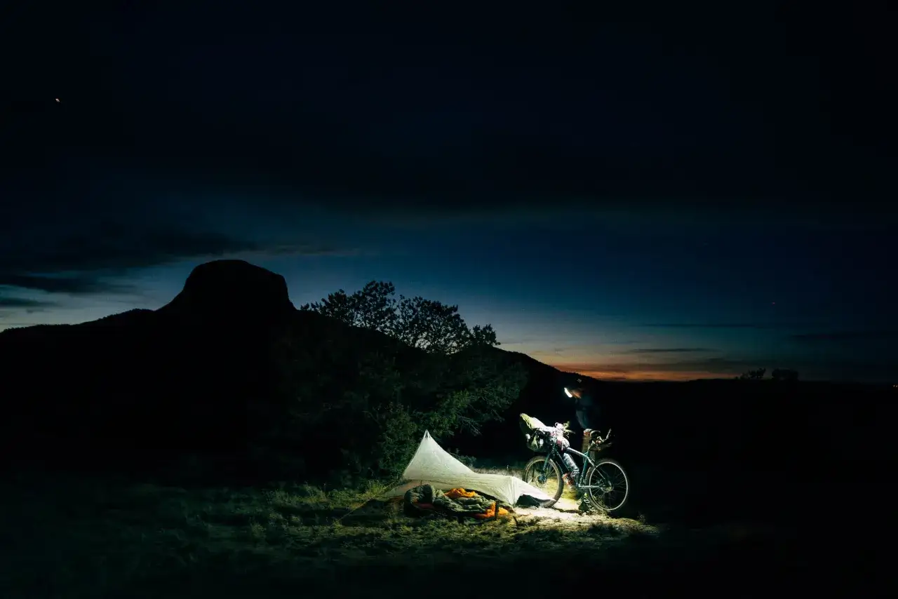 Ein Radfahrer bereitet sich auf eine Nacht im Freien vor, ein Zelt und Schlafsack sind bereit. Das Abenteuer des ultra cycling beginnt im Dunkeln.