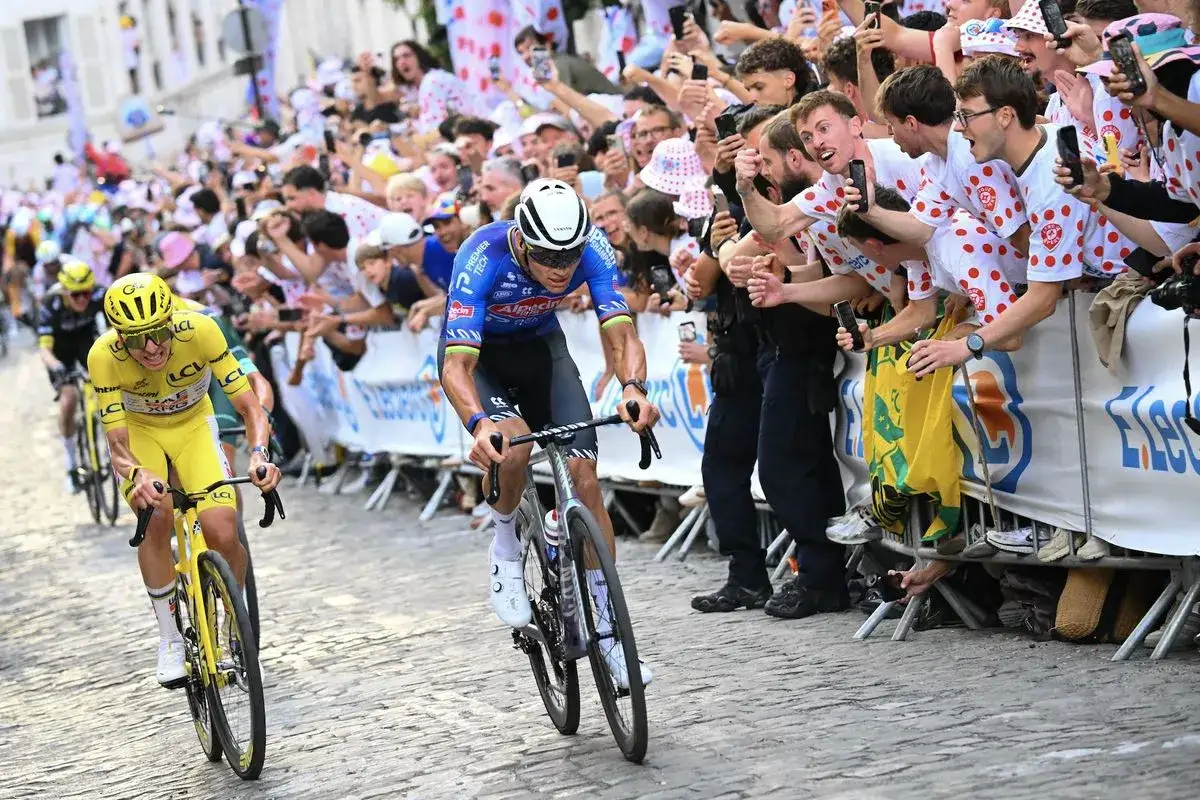 Radfahrer in Gelb und Blau kämpfen sich durch eine jubelnde Menge. Die Spannung steigt, wo endet die Tour de France?