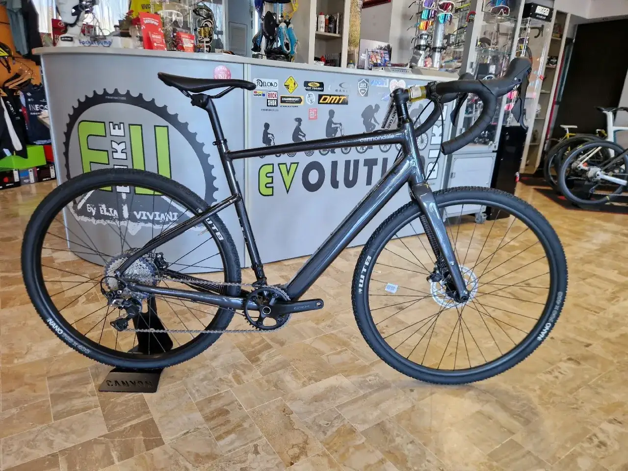 Graues Cannondale Topstone Neo SL 2 Gravelbike im Laden. Das geringe cannondale topstone neo sl 2 gewicht macht es ideal für lange Touren.