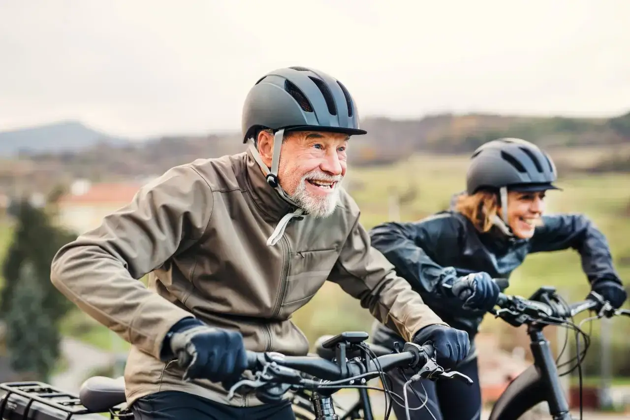 Glückliches älteres Paar testet e-Bikes auf einer Fahrt durch die Natur.