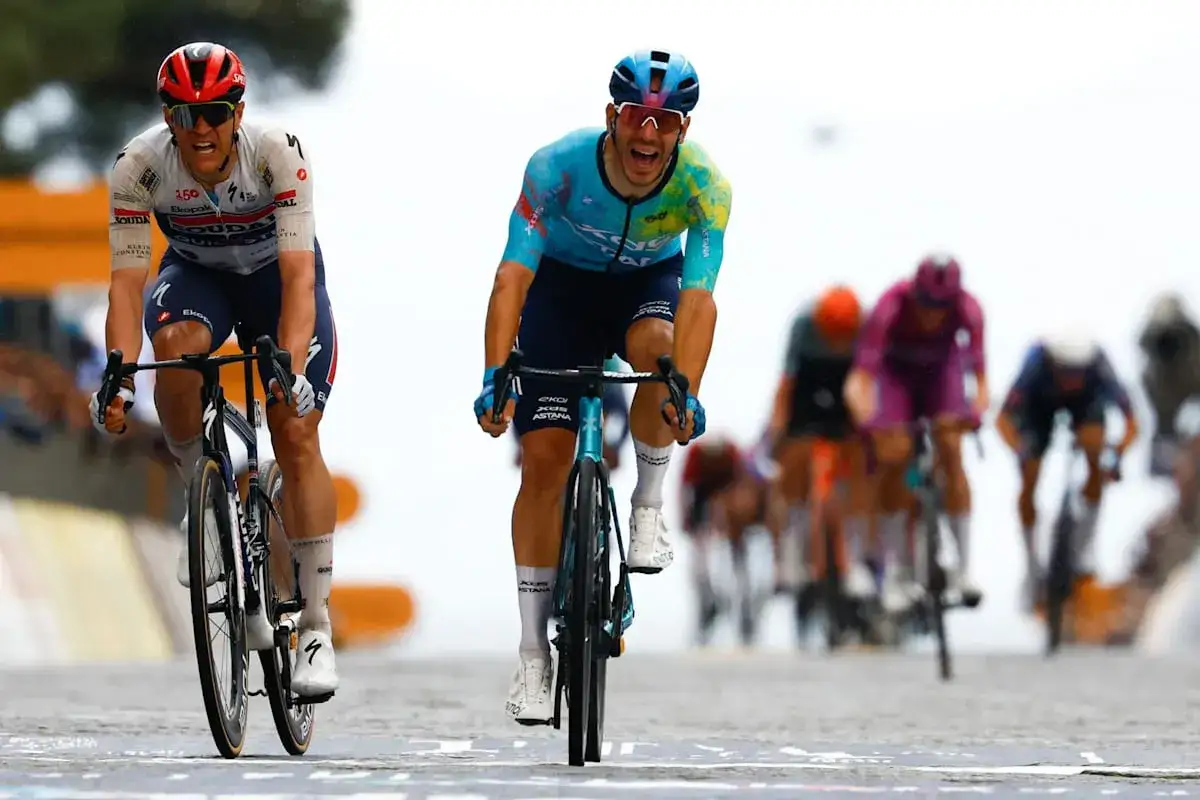 Zwei Radfahrer kämpfen um die Führung im Giro d'Italia Gesamtwertung. Der Fahrer im blauen Trikot jubelt, während sein Konkurrent konzentriert bleibt.