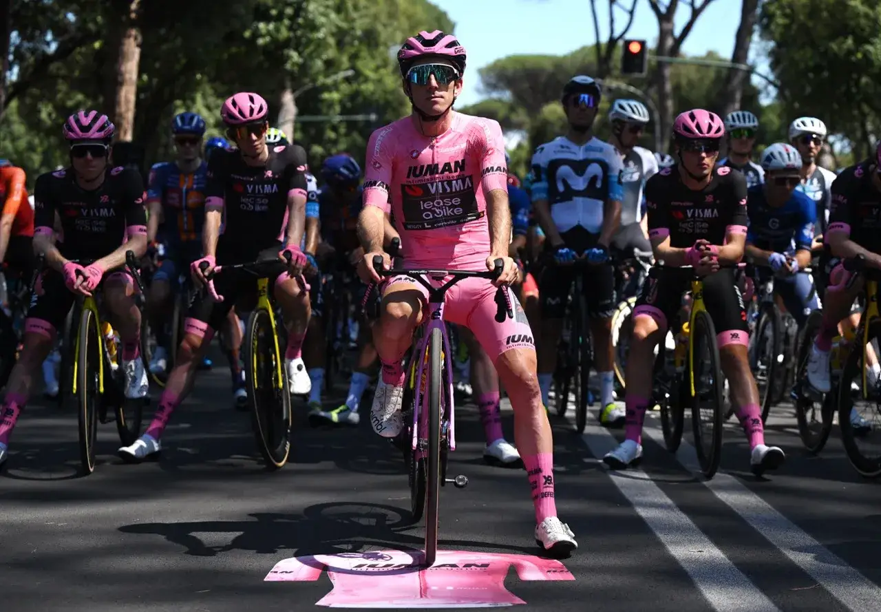 Radfahrer in rosa Trikots, die auf ihre Räder warten. Die