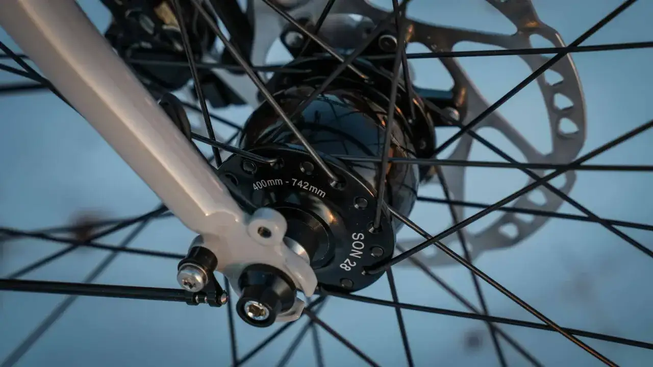 Nahaufnahme einer Fahrradnabe mit Speichen und Bremsscheibe. Die Nabe trägt die Aufschrift