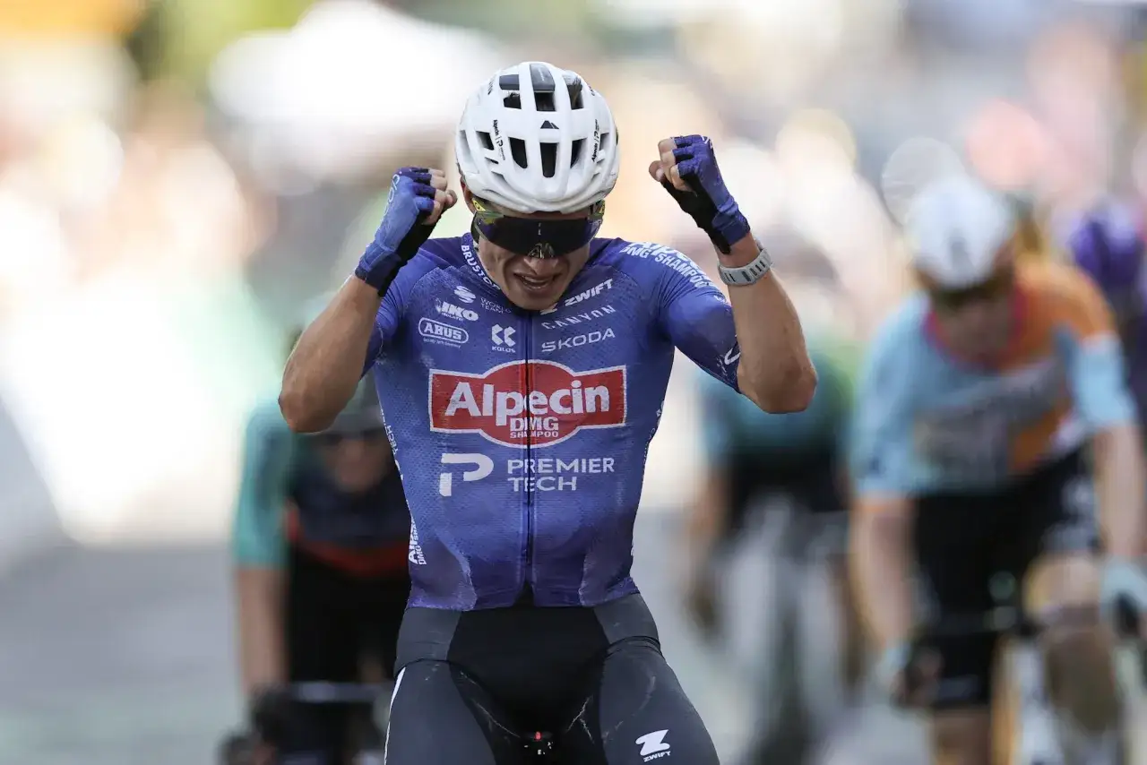 Jasper Philipsen jubelt nach einem Sieg, die Fäuste geballt. Er trägt ein blaues Radtrikot mit Alpecin-Logo.