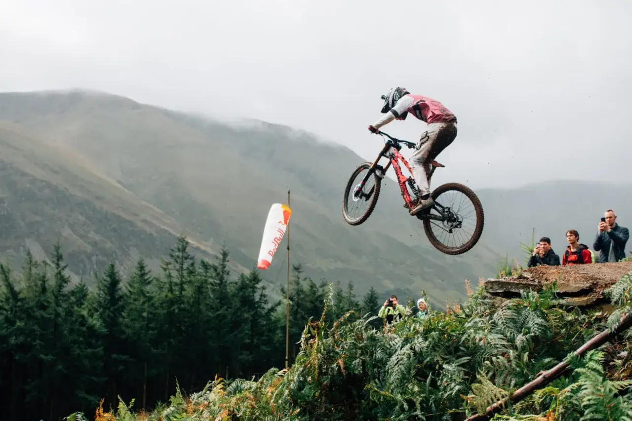 Gabriel Wibmer fliegt mit seinem Mountainbike durch die Luft, während Zuschauer am Rand stehen.